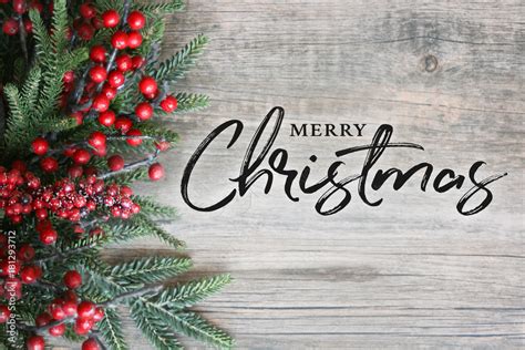 Merry Christmas Text With Christmas Evergreen Branches And Berries In Corner Over Rustic Wooden