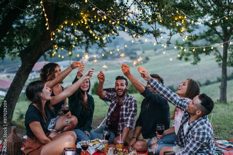 Group Of Happy Millennials Have Fun With Fire Sparkles At Picnic In