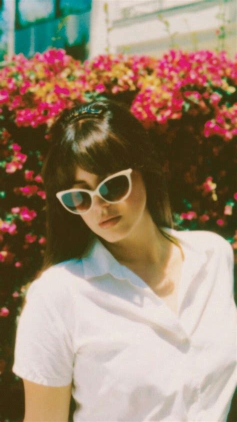 a woman wearing sunglasses standing in front of flowers