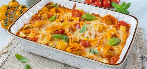 A Casserole Dish With Tomatoes Cheese And Spinach On The Side Next To