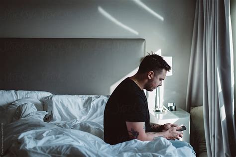 Horizontal Portrait Of Urban Male Using His Mobile Phone At Home By