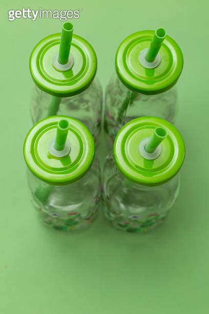 Glass Bottle With A Straw In Green On A Green Background Portrait