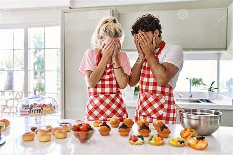 Couple Of Wife And Husband Cooking Pastries At The Kitchen With Sad Expression Covering Face