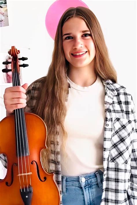 A Girl Holding A Violin In Her Right Hand And Wearing A Pink Hat On Top