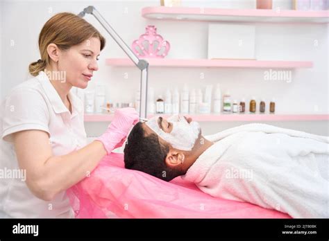 Cosmetician applying kaolin mask to man facial skin Stock Photo - Alamy
