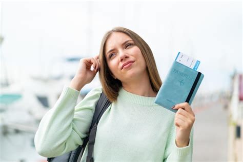 Junge hübsche blonde Frau einen Pass hält und Zweifel hat Premium Foto