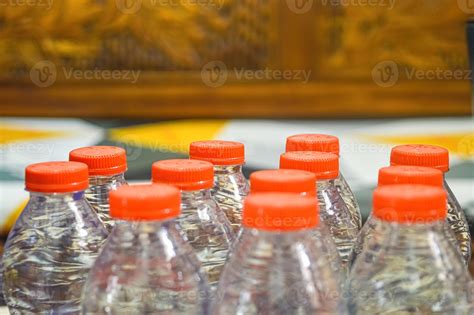 Many Plastic Mineral Water Bottles With Orange Caps On Blur Background
