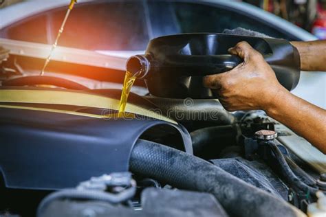 Car Mechanic Replacing And Pouring Fresh Oil Into Engine At Maintenance