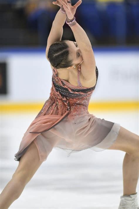 A Woman Skating On An Ice Rink Wearing A Dress And Holding Her Arms Up