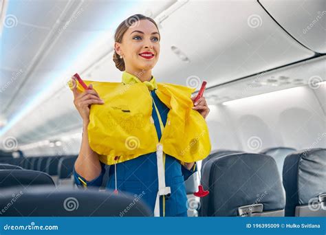 Flight Attendant On Board An Airplane Holding Life Jacket Before Flight