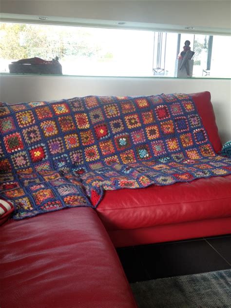 A Red Couch With A Colorful Blanket On It In Front Of A Large Window