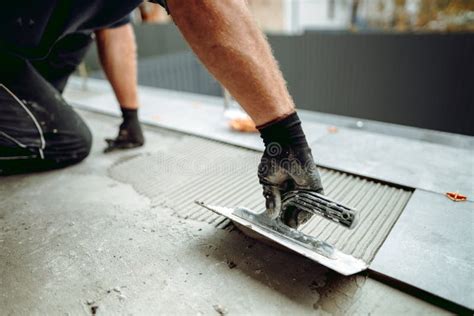 Hand Of Professional Construction Worker Placing Floor Tiles On