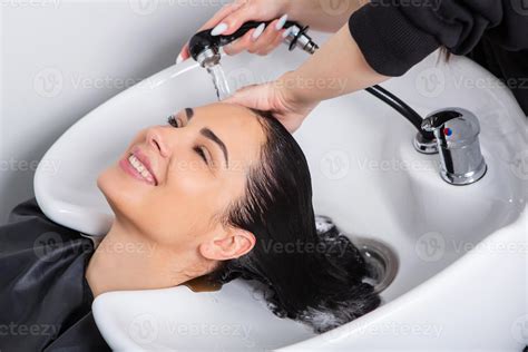 Professional Hairdresser Washing Hair Of Young Woman In Beauty Salon