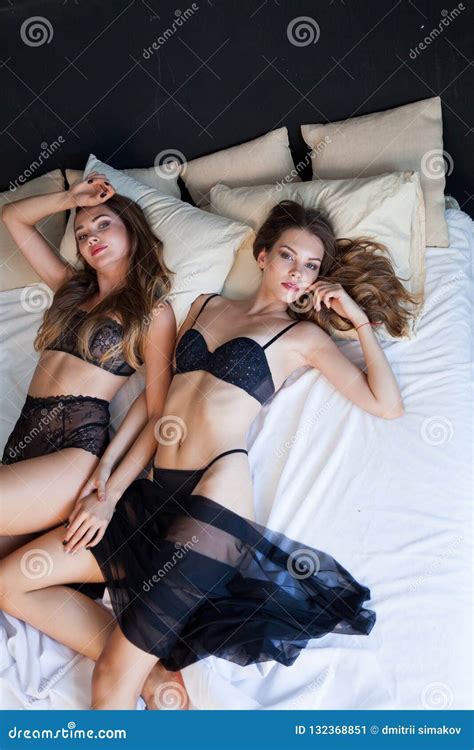 Two Beautiful Fashionable Woman In Lingerie Lying On A Bed In The