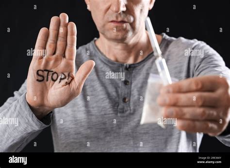 Mature Junkie With Drugs And Word Stop On His Palm Against Black