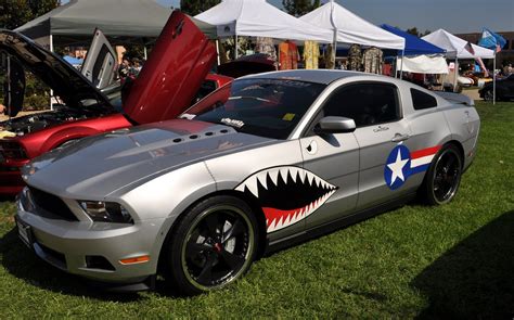 A Silver Mustang With A Sharks Teeth Painted On The Hood At A Car Show