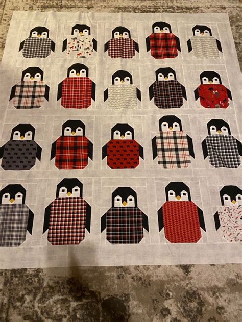 A Quilted Table Topper With Penguins In Red Black And White On It