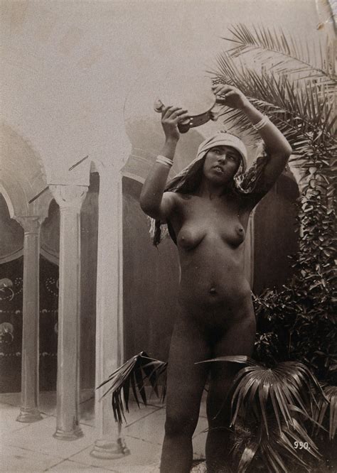 A Woman Posing Naked In A Photographic Studio Holding Aloft A