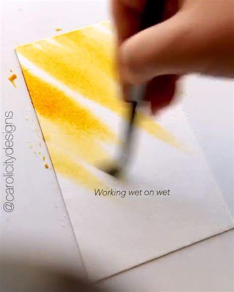 A Person Is Using A Brush To Paint The Paper With Yellow Watercolors On It