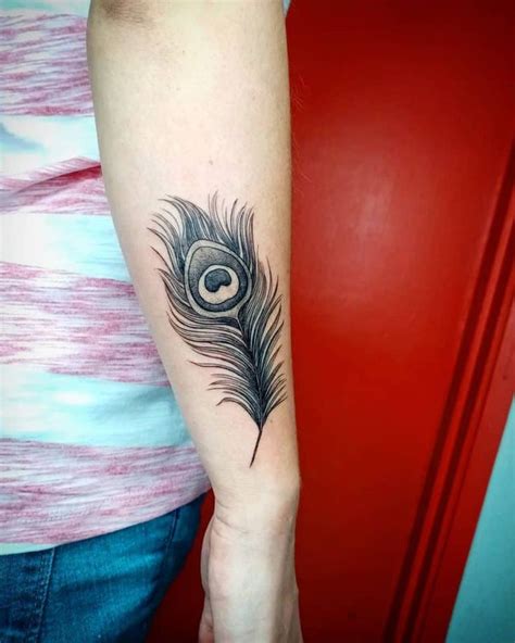 A Woman S Arm With A Black And White Peacock Feather Tattoo On The Left