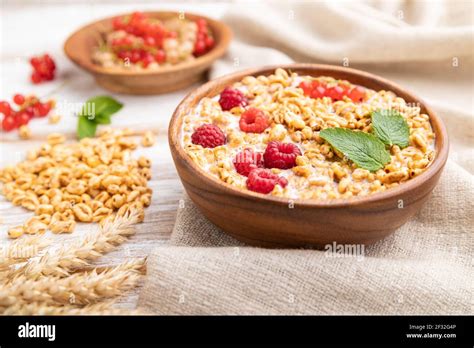 Wheat Flakes Porridge With Milk Raspberry And Currant In Wooden Bowl