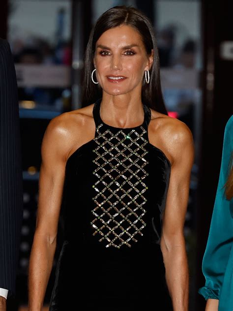 A Woman In A Black Dress Is Smiling At The Camera While Standing Next