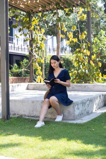 Premium Photo Portrait Of Young Woman Sitting On Grass Against Plants