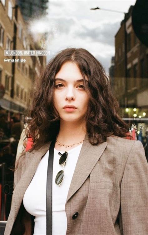 A Woman Standing In Front Of A Store Window Wearing A Suit And Tie With