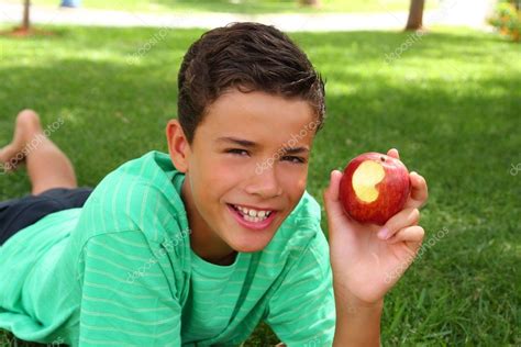 Boy teenager eating red apple on garden grass — Stock Photo ...