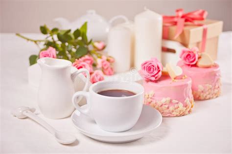 A Cup Of Tea Pink Roses And Small Cakes On The White Table Stock Image