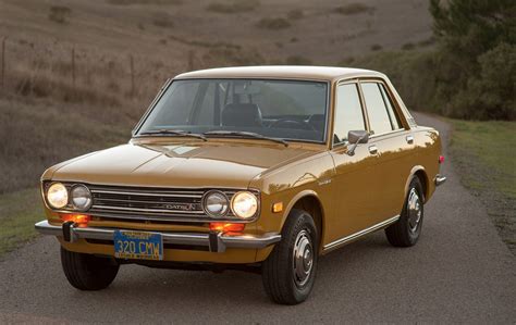 An Old Car Is Parked On The Side Of The Road In Front Of Some Hills