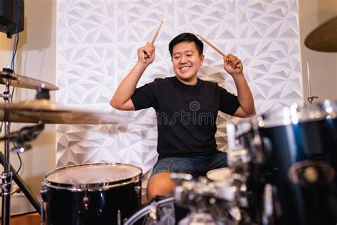 A Male Drummer Holding Drumsticks While Playing Drums With A Band Stock