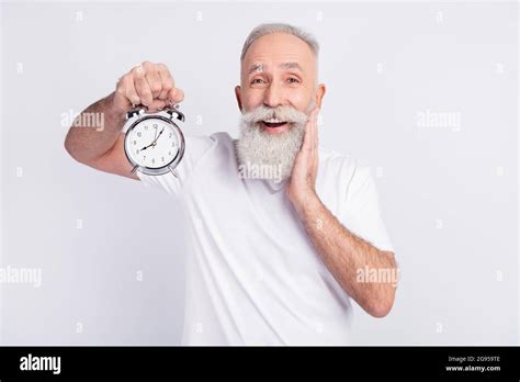 Photo Of Happy Cheerful Old Man Hold Hand Cheekbone Clock Alarm Good