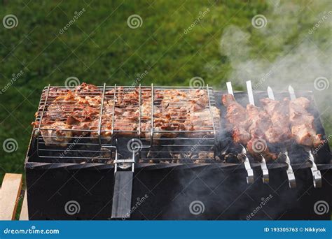 Grill Barbecue Meat On A Brazier With Smoke Green Grass Background