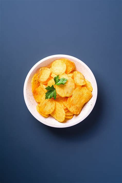 Fried Corrugated Golden Potato Chips With Parsley Leaf In Wooden Bowl