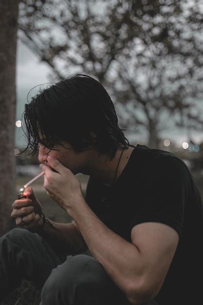 Premium Photo Side View Of Man Smoking Cigarette While Sitting Outdoors