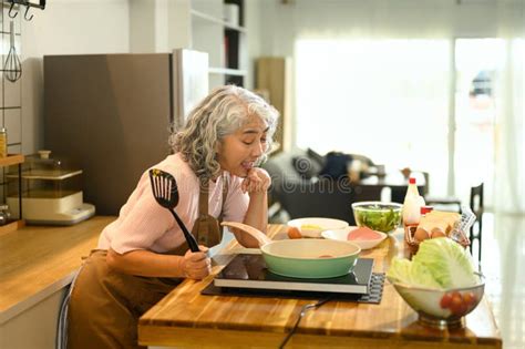 Happy Mature Woman Holding Spatula Cooking At A Modern Kitchen Counter Stock Image Image Of