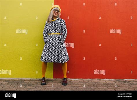 Cheerful Mature Woman Smiling At The Camera While Standing Against A Colourful Background Happy