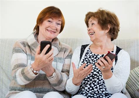 Smiling Mature Women Browsing Internet On Smarthphones Stock Image