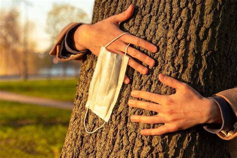 Premium Photo Hands Embracing Tree Takes Off Medical Protective Mask