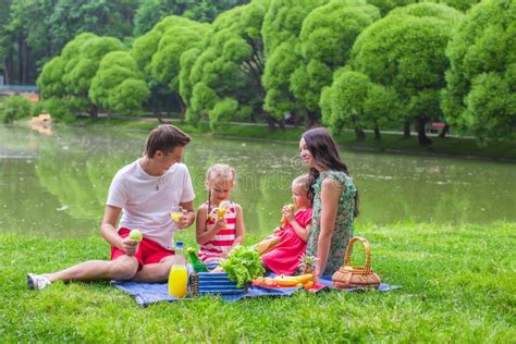 Familia Feliz Que Merienda En El Campo En El Parque Foto De Archivo