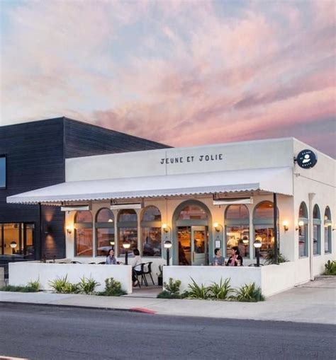 The Exterior Of A Restaurant With White Walls And Black Trimmings On A