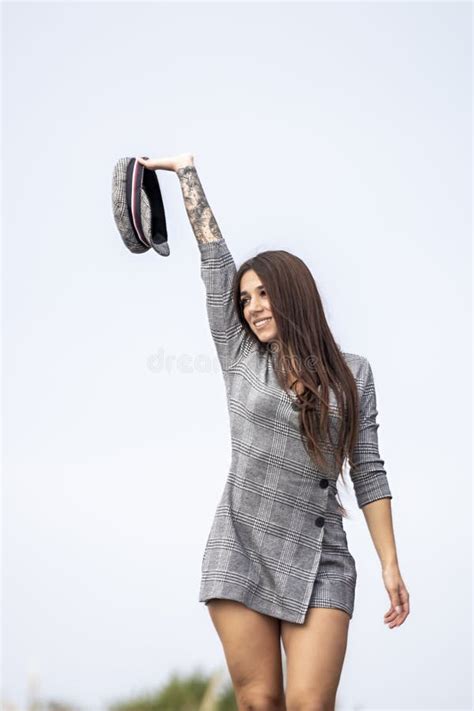 Youthful Urban Elegance A Confident Brunette In A Short Dress And Hat