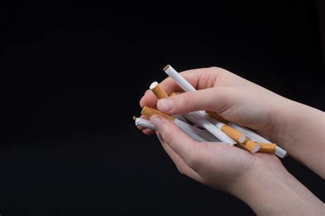 Premium Photo Cropped Hands Of Person Holding Cigarettes Over Black