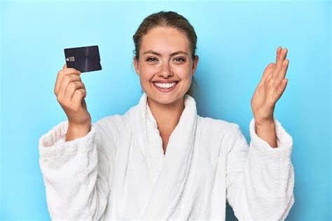 Premium Photo Blonde In Bathrobe With Credit Card In Blue Studio Receiving A Pleasant Surprise