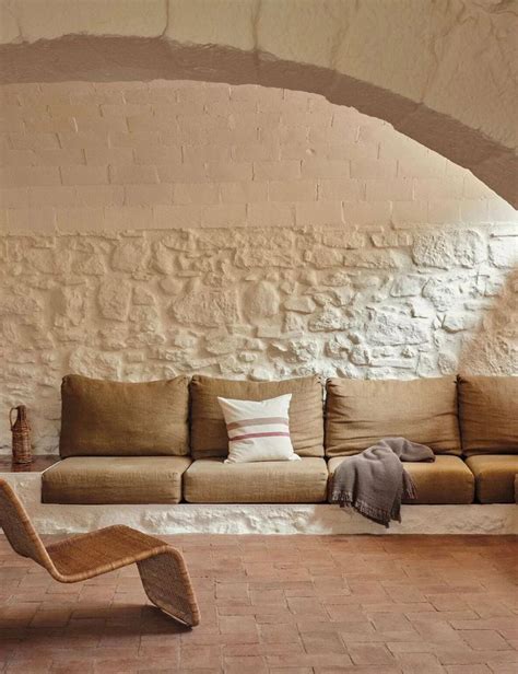 A Living Room Filled With Furniture Next To A Stone Wall Covered In