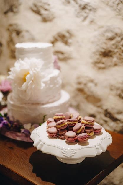 Premium Photo Macaroon Cakes Lie On A Stand Next To A Wedding Cake On