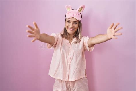 Blonde Caucasian Woman Wearing Sleep Mask And Pajama Looking At The Camera Smiling With Open