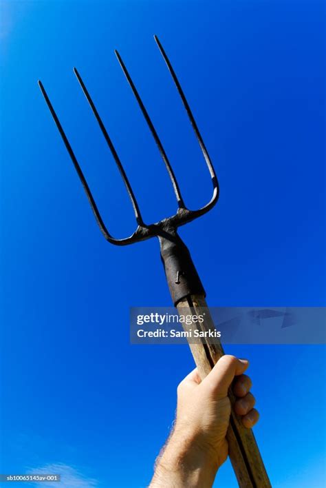 Mans Hand Holding Up Pitchfork Against Blue Sky High Res Stock Photo