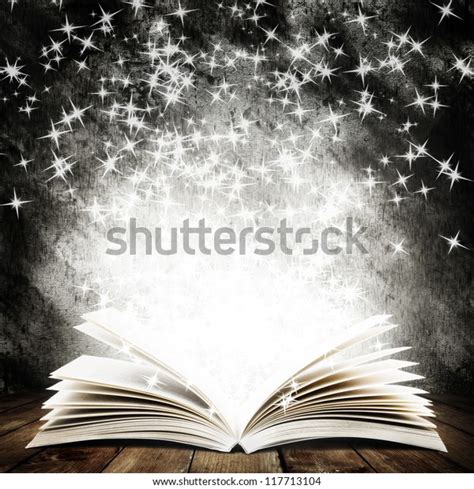 Livro aberto antigo luz mágica e estrelas caindo em tábuas de